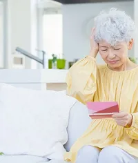 通帳を確認して悩む女性